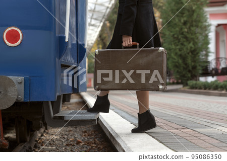 Girl in retro clothes with leather vintage suitcase travels in train. Woman traveler. Girl in retro clothes with leather vintage suitcase travels in train. Woman traveler. 95086350