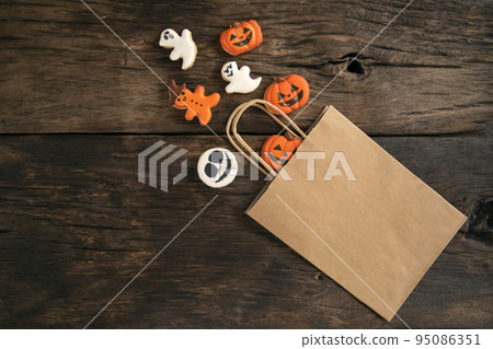 Decorations for Halloween made of orange and white ginger cookies from bag. Pumpkin and ghosts. Halloween sweets 95086351