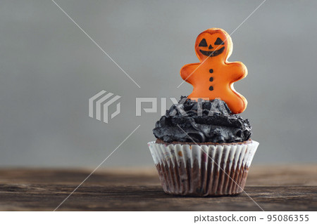 Festive Halloween cupcakes decorated with gingerbread man on wooden table on grey background. Delicious halloween party muffins. Festive Halloween cupcakes decorated with gingerbread man on wooden table on grey background. Delicious halloween party muffins. 95086355