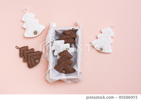 Christmas handmade. Knitted fir-trees in a gift box on a pastel color. Handicraft and leisure 95086955