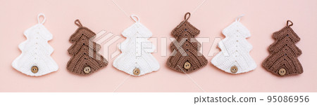 Christmas handmade. Knitted fir-trees in a row on a pastel background. Handicraft and leisure. Web banner 95086956