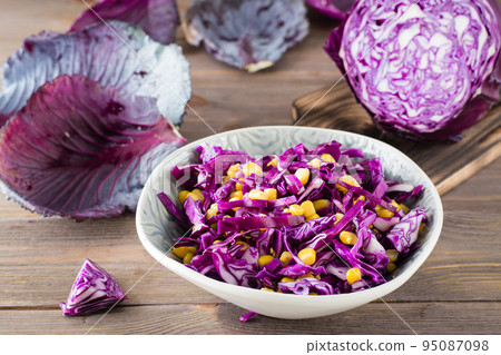 Red cabbage salad with corn grains in a plate on a wooden table. Vegetarian food Red cabbage salad with corn grains in a plate on a wooden table. Vegetarian food 95087098