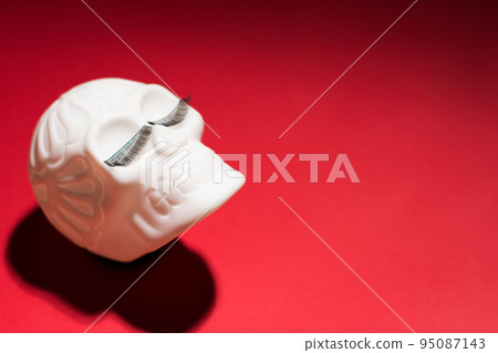 Cheerful Human skull with eyelashes on a red background.  95087143