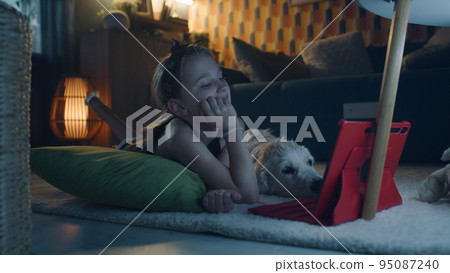 Young girl chosing movie to watch with dog 95087240