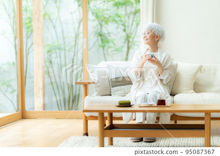 Silver-haired woman drinking tea 95087367