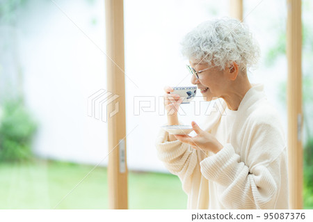 Silver-haired woman drinking tea Silver-haired woman drinking tea 95087376