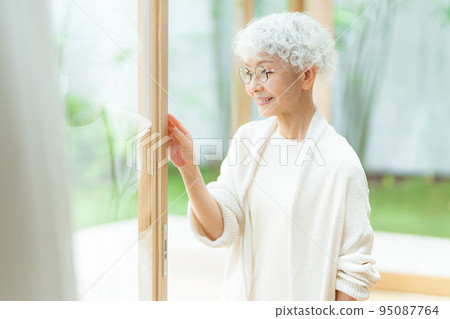 Senior woman looking out the window 95087764