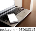 Smartphone white screen mockup on a laptop computer black keyboard white screen mock-up on a desk office with copy space and composition. The concept for using an advertising banner text 95088315