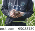 Smart Farming Concept. The farmer is using his mobile phone with Smart farmer agriculture technology to control the quality of the farm. Icons show on the smartphone display. 95088320