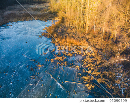 Aerial view on frozen wild lake in sunset forest Aerial view on frozen wild lake in sunset forest 95090599
