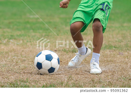 Football soccer children training class. Kindergarten and elementary school kids playing football in a field. Group of boys running and kicking soccer on sports grass pitch. Selective focus on ball. Football soccer children training class. Kindergarten and elementary school kids playing football in a field. Group of boys running and kicking soccer on sports grass pitch. Selective focus on ball. 95091362