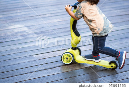 Asian kid enjoy playing and riding scooter without using any safety gear in home. Active lifestyle of children in nature. Happy little boy ride scooter without helmet. Active sport for preschool kid. Asian kid enjoy playing and riding scooter without using any safety gear in home. Active lifestyle of children in nature. Happy little boy ride scooter without helmet. Active sport for preschool kid. 95091363
