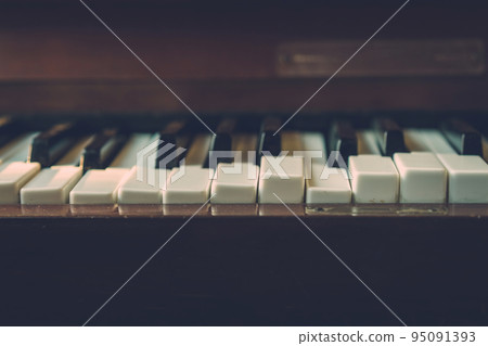 Close up shot to broken piano keys in abandoned house. An ancient musical instrument. Old broken disused piano with damaged keys Vintage Retro Filter. Distressed Piano made of wood. Selective Focus. 95091393