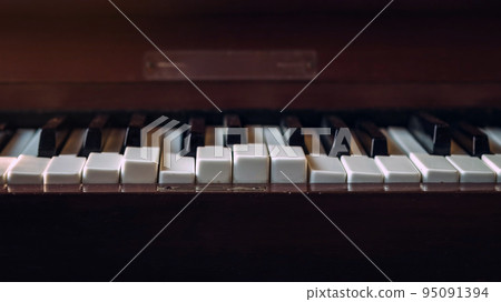 Close up shot to broken piano keys in abandoned house. An ancient musical instrument. Old broken disused piano with damaged keys Vintage Retro Filter. Distressed Piano made of wood. Selective Focus. 95091394