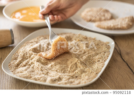 Final stage of coating meat in breadcrumbs while making schnitzels 95092118