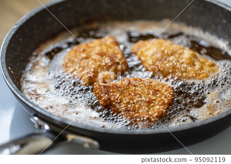 Breaded schnitzels are frying in a sizzling pan making the traditional vienese food 95092119
