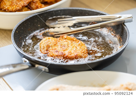 Pan full of oil is used for frying breaded meat while making wiener schnitzels 95092124