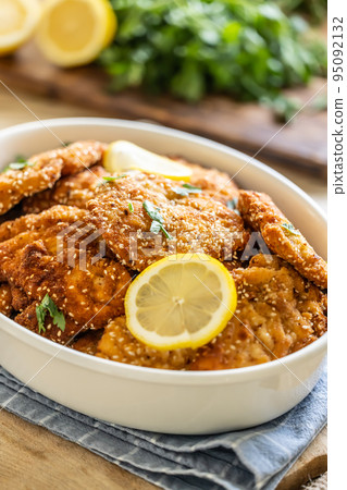 Detail of crispy fresh schnitzels with sesame seeds served with slice of lemon and parsley Detail of crispy fresh schnitzels with sesame seeds served with slice of lemon and parsley 95092132