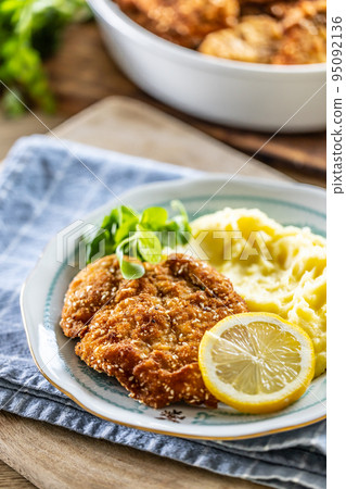 Traditional schnitzel with potato mash and green salad served on a plate 95092136