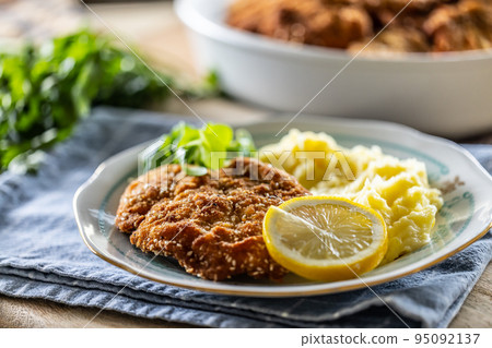 Breaded meat served with potato mash, slice of lemon and greens 95092137