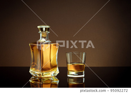 close up view of bottle of brandy and glass aside on color back.  95092272
