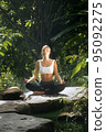 Portrait of young woman practicing yoga in tropic environment 95092275