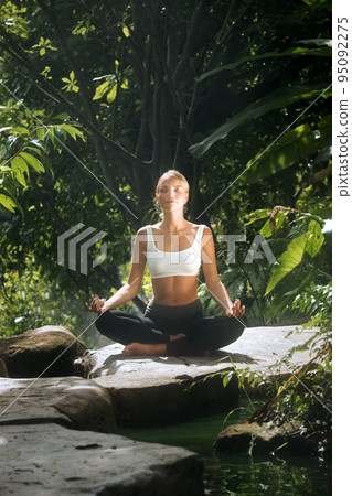 Portrait of young woman practicing yoga in tropic environment 95092275
