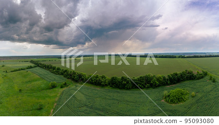Aerial fly above green fields, stormy cloudscape 95093080