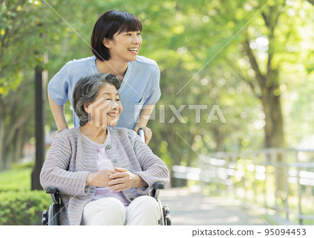 Female healthcare worker pushing senior woman's wheelchair 95094453