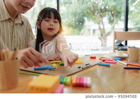 Adorable little girl and father playing with colorful plasticine. Handmade skills training Adorable little girl and father playing with colorful plasticine. Handmade skills training 95094588