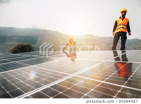 Workers assemble energy system with solar panel for electricity Workers assemble energy system with solar panel for electricity 95094987