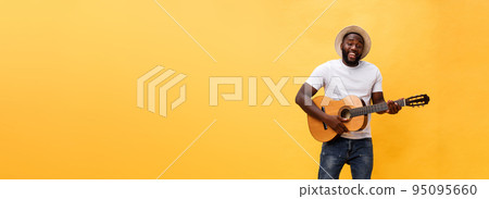 Full-length photo of excited artistic man playing his guitar in casual suite. Isolated on yellow background. 95095660
