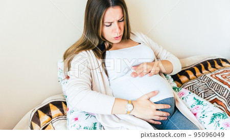 Pregnancy contractions time. Childbirth time, contractions pain. Pregnant holding baby belly, woman watching clock. Therapy, healthcare, motherhood concept. Pregnancy contractions time. Childbirth time, contractions pain. Pregnant holding baby belly, woman watching clock. Therapy, healthcare, motherhood concept. 95096049