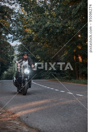 Blurred Motion A young man biker in a helmet quickly rides at high speed on a forest road, in motion 95096274
