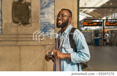 Smiling black tourist man at portuguese train station 95097278