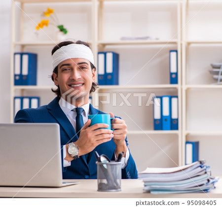 Head injured male employee working in the office Head injured male employee working in the office 95098405
