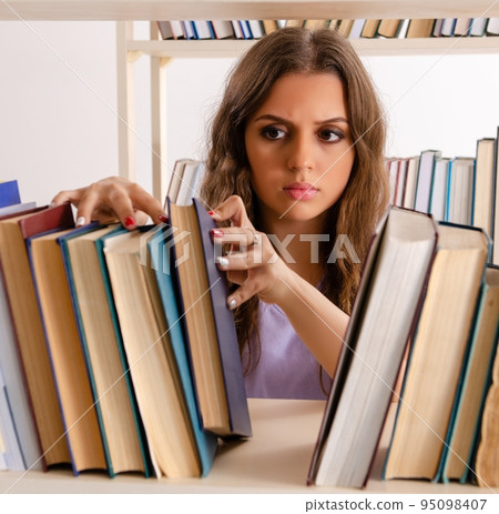 Young female student preparing for exams at library Young female student preparing for exams at library 95098407