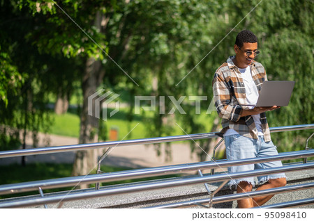 A man with a laptop working outside and looking involved A man with a laptop working outside and looking involved 95098410