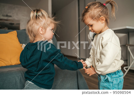 Two cute sisters playing together in the room 95098504