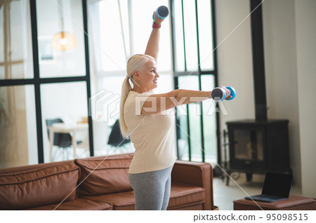 Joyful woman doing a strength training exercise 95098515