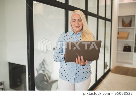 Concentrated blonde woman using her portable computer 95098522