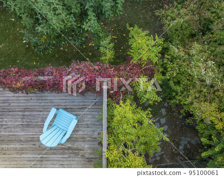empty Adirondack chair on a wooden backyard deck empty Adirondack chair on a wooden backyard deck 95100061