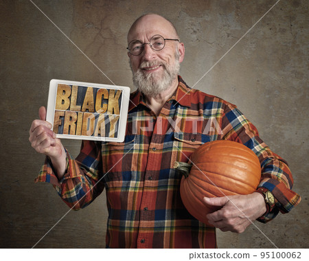 Black Friday sign - smiling senior man with pumpkin 95100062