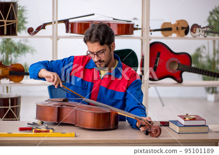 Young man repairing musical instruments at workshop 95101189
