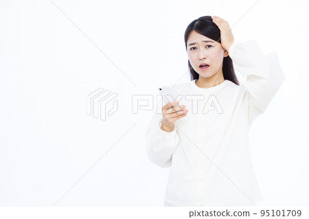 A woman in her thirties who is surprised to hold her head with a smartphone 95101709