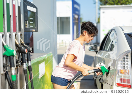 Smiling woman refueling her car in gas station Smiling woman refueling her car in gas station 95102015