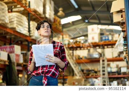 Female storekeeper checks presence of goods in the building materials warehouse 95102114