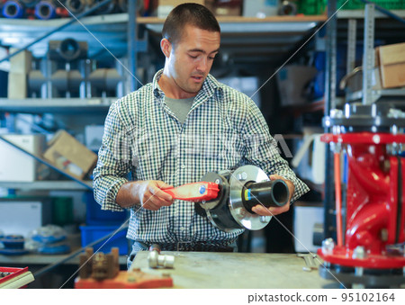 Base for the valve is installed and clamped in a vice for assembly at the factory and the worker installs and fastens components 95102164