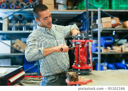 Base for the valve is installed and clamped in a vice for assembly at the factory and the worker installs and fastens components 95102166