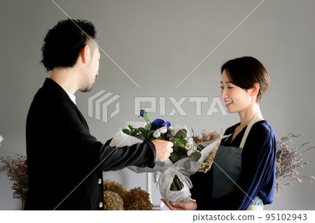 A person who comes to buy a bouquet at a flower shop or a person who gives flowers to his wife 95102943